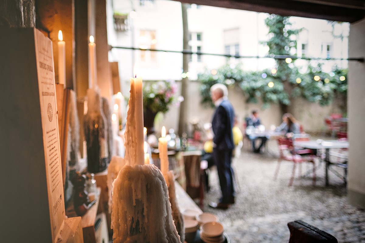 Gegenüber vom Rubino, im Innenhof der Invino-Weinbar, sorgen Kerzenlicht, Kieselsteinboden und Blechgartenmobiliar fürs Ambiente.